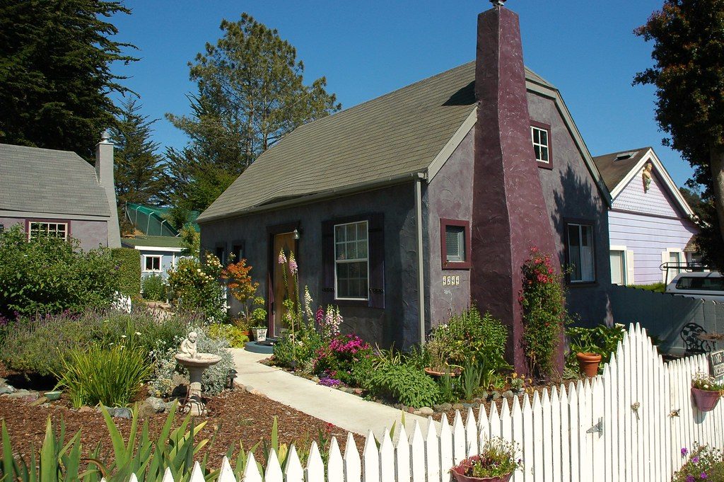 A California cottage behind a white picket fence and a planted front garden